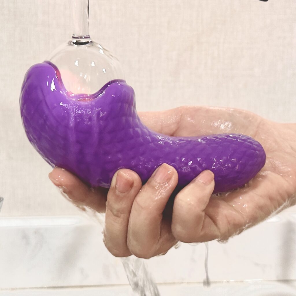 A person is washing a purple vibrator, highlighting the vibrator's waterproof function and easy cleaning.